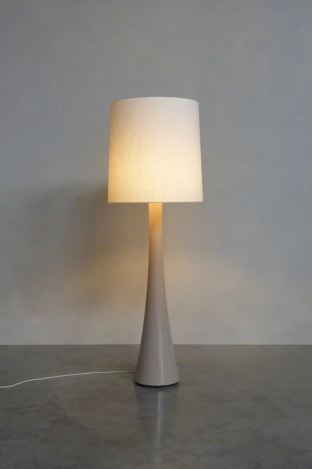 Fontein & Bova OSCAR No. 3 – handcrafted Belgian floor lamp with conical grey base and warm linen drum shade, lit against a n