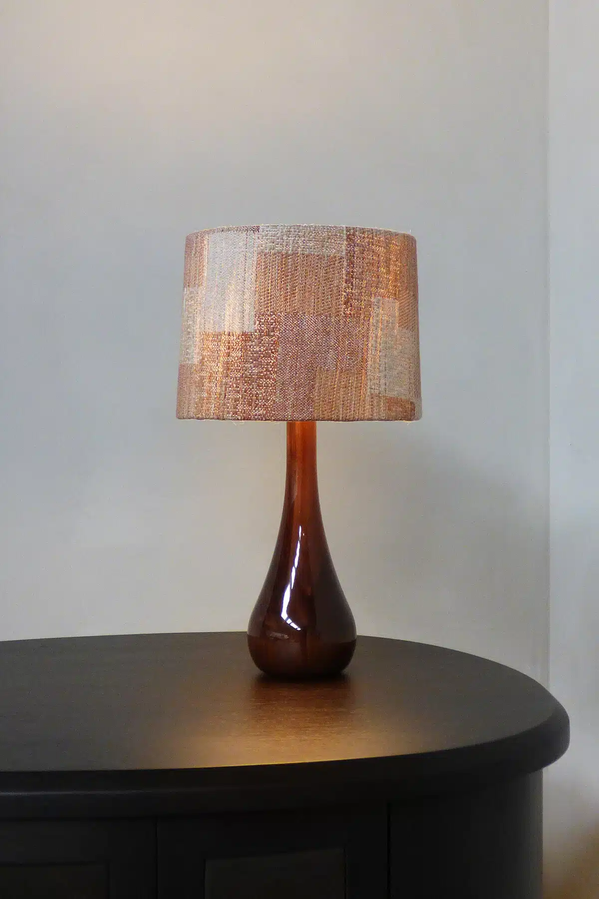 RENÉE – NO. 1 table lamp by Fontein & Bova featuring a glossy amber teardrop ceramic base and textured woven drum shade on a
